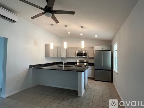 A kitchen with a black countertop and stainless steel appliances.