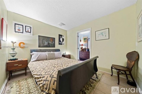 A bedroom with a large bed and a chair.