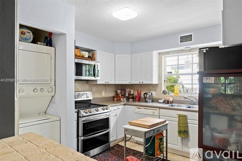 A kitchen with white cabinets and appliances is available for rent.