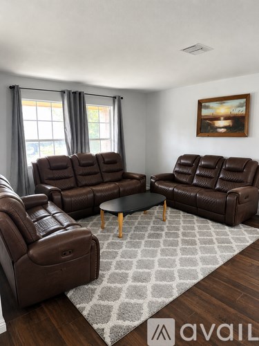 A living room with brown leather furniture and a grey rug.