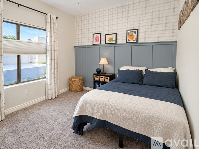 A bedroom with a large bed and a window with blinds.