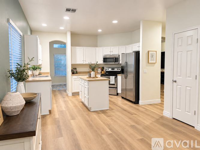 A modern kitchen with white cabinets and a wooden floor.