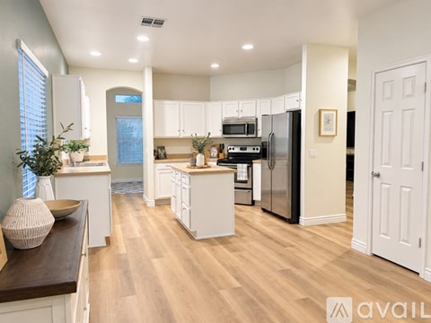 A modern kitchen with white cabinets and a wooden floor.
