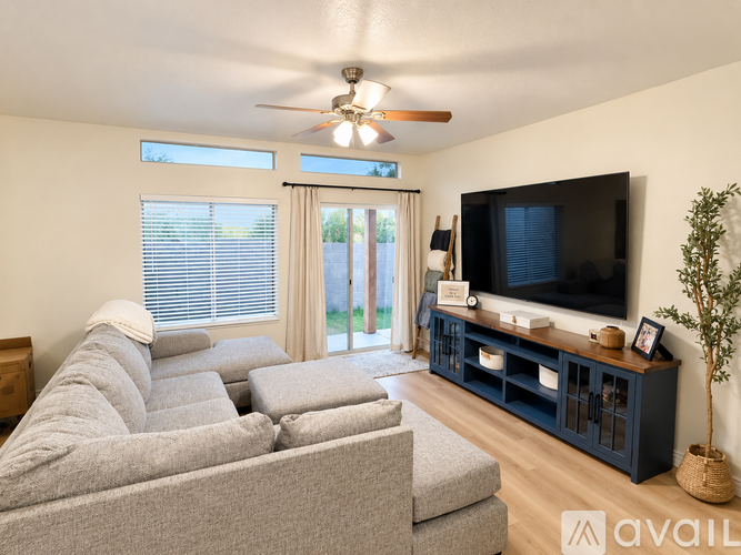 A living room with a grey couch, a television, and a ceiling fan.