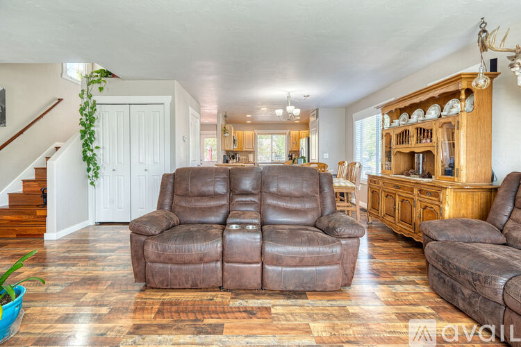 A living room with a brown leather couch and wooden floors.