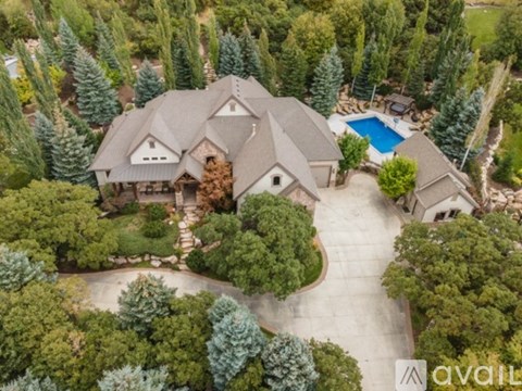 A large house with a pool surrounded by trees.