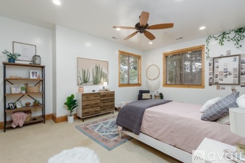 A bedroom with a bed, dresser, and a ceiling fan.