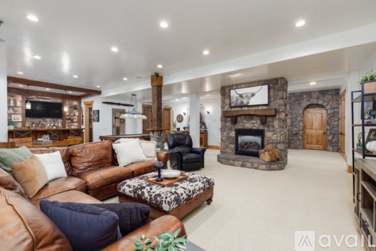 A living room with a stone fireplace and a large leather couch.