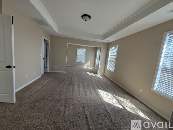 A spacious room with carpeted floor and a door on the left.