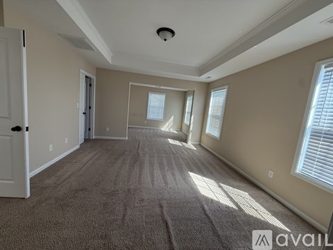 A spacious room with carpeted floor and a door on the left.