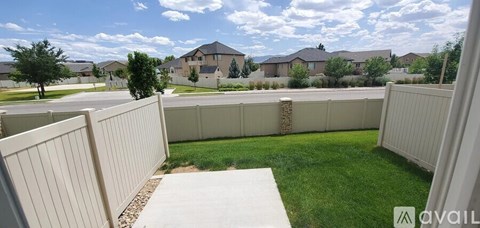 A white fence in a grassy area with a house in the background.
