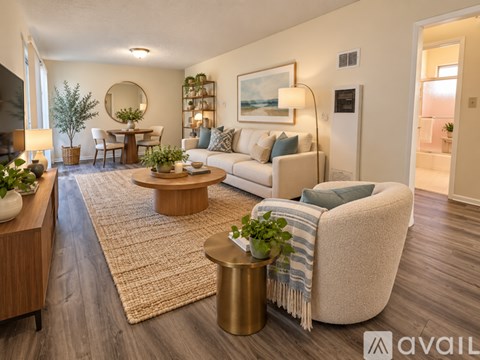 A living room with a white couch, a coffee table, and a round mirror on the wall.