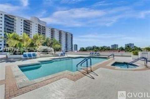 A swimming pool surrounded by a brick patio and apartment buildings in the background.