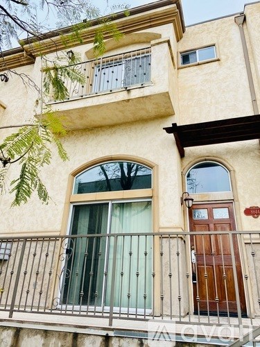 A building with a balcony and a window with a green curtain.