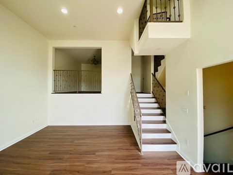 A spacious room with wooden floors and a staircase leading to another level.