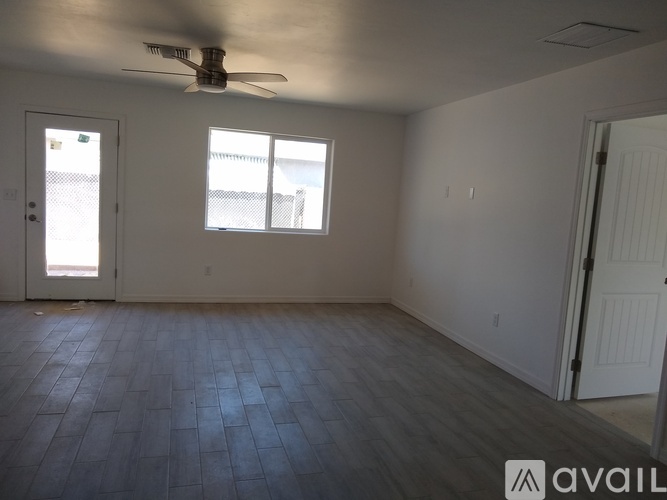 A room with a ceiling fan and two windows.