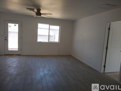 A room with a ceiling fan and two windows.