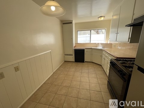 A kitchen with white cabinets and a black dishwasher.