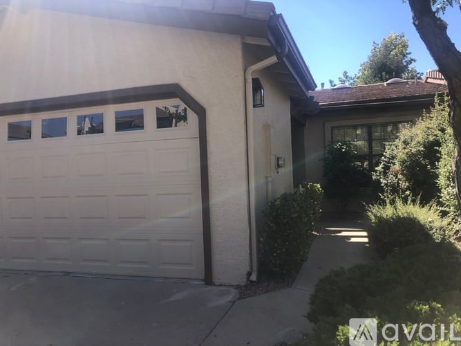 A house with a white garage door and a tree in front.