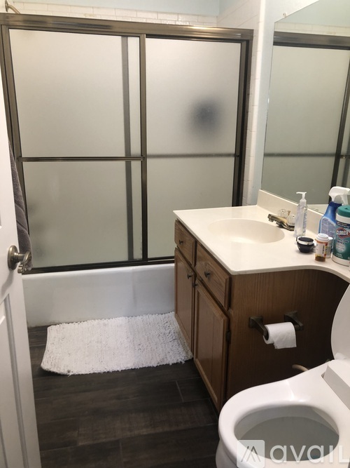 A white toilet sits in a bathroom next to a sink and a glass shower door.