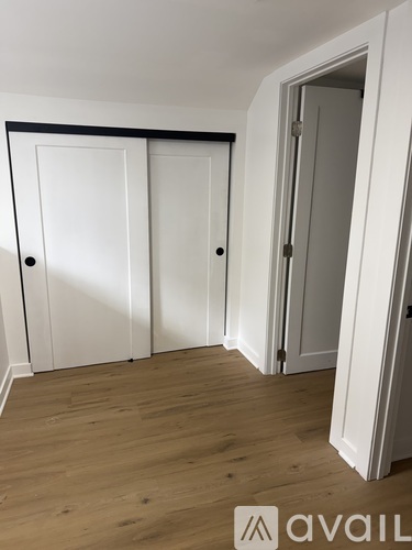 Three white doors in a room with wooden floors.