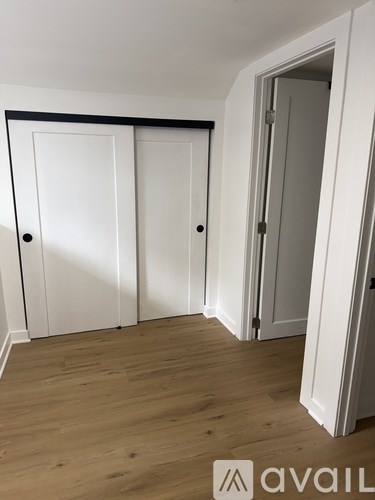 Three white doors in a room with wooden floors.