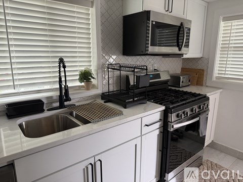 A kitchen with white cabinets and black appliances.