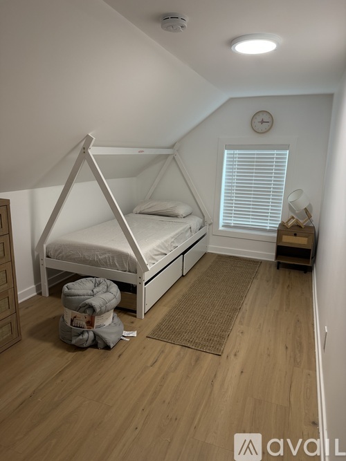 A bedroom with a bed and a window with blinds.
