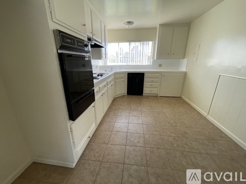 A kitchen with white cabinets and a black oven.