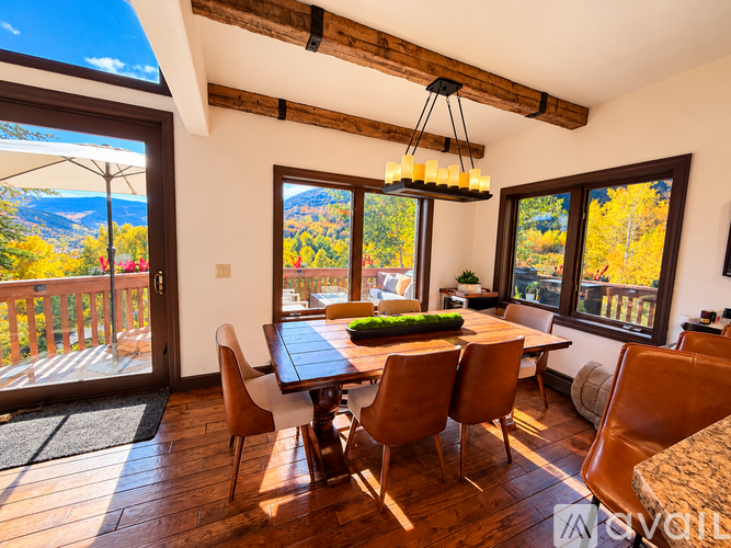 A dining room with a table and chairs and a view of the mountains.