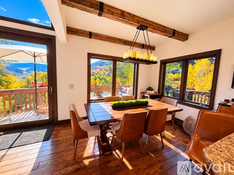 A dining room with a table and chairs and a view of the mountains.