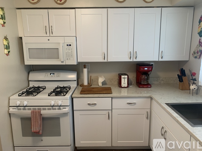 A kitchen with white cabinets and a white stove top oven.