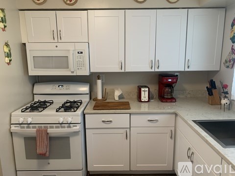 A kitchen with white cabinets and a white stove top oven.
