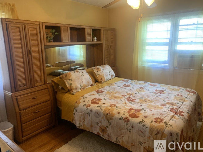 A bedroom with a bed, wooden furniture, and a window.