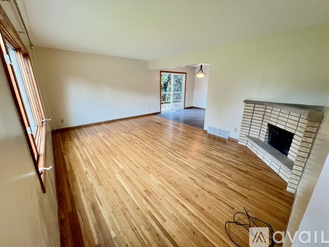 A room with wooden flooring and a fireplace.