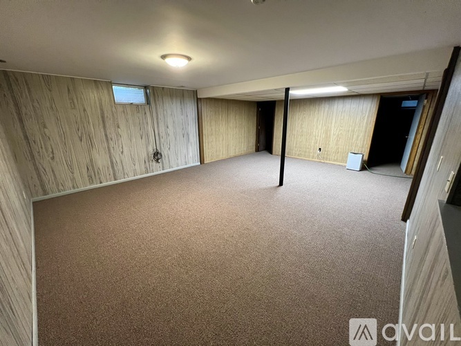 A spacious room with wooden walls and carpeted floor.
