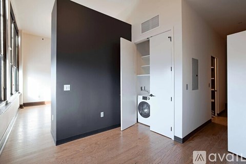 A black wall with a white door and a washing machine in a room.