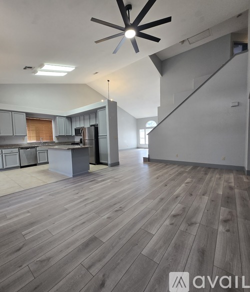 A spacious kitchen with a wooden floor and a ceiling fan.
