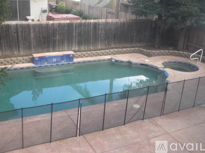 A pool surrounded by a black fence and a small blue pool in the middle.