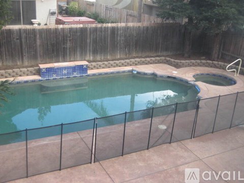 A pool surrounded by a black fence and a small blue pool in the middle.