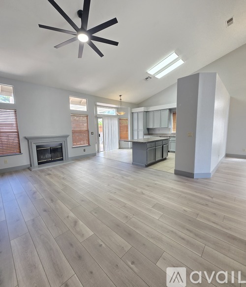 A spacious living room with a fireplace and a ceiling fan.