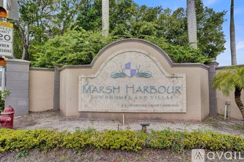 A sign for Marsh Harbour Townhomes and Villas is displayed in front of a building.