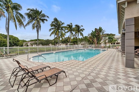 A pool surrounded by palm trees and lounge chairs.