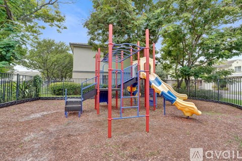 A playground with a red and blue structure and a yellow slide.