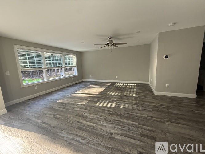 A spacious room with a ceiling fan and a large window.