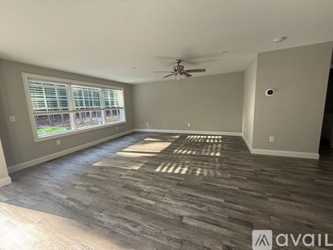 A spacious room with a ceiling fan and a large window.