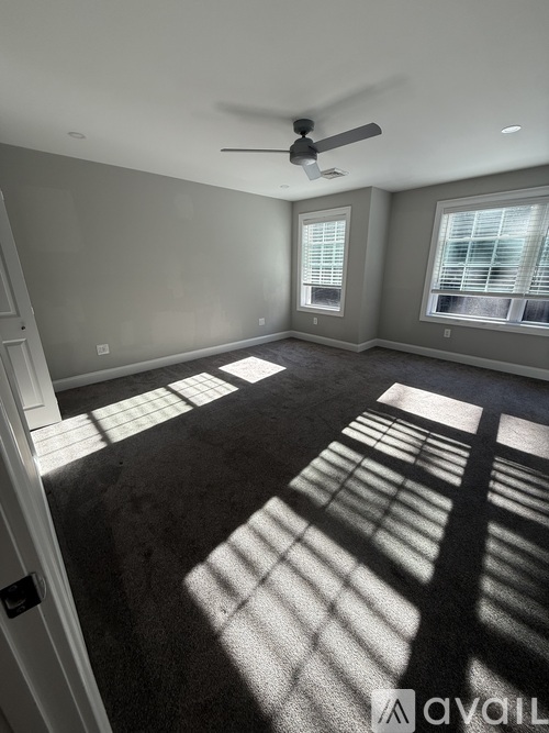 A room with a carpet floor and a ceiling fan.