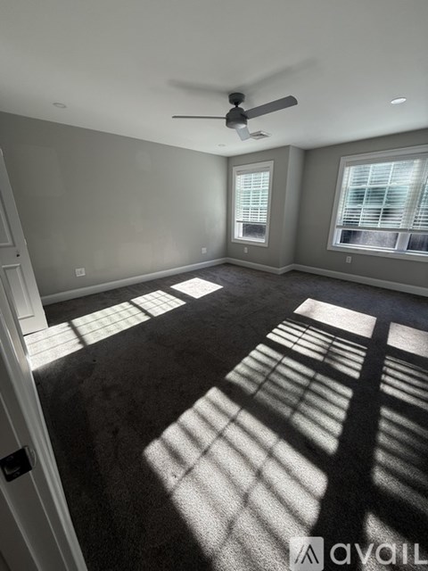 A room with a carpet floor and a ceiling fan.
