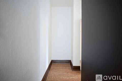 A hallway with a wooden floor and white walls.