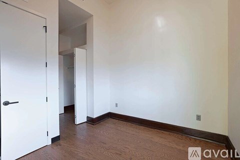 A room with a white door and wooden floor.